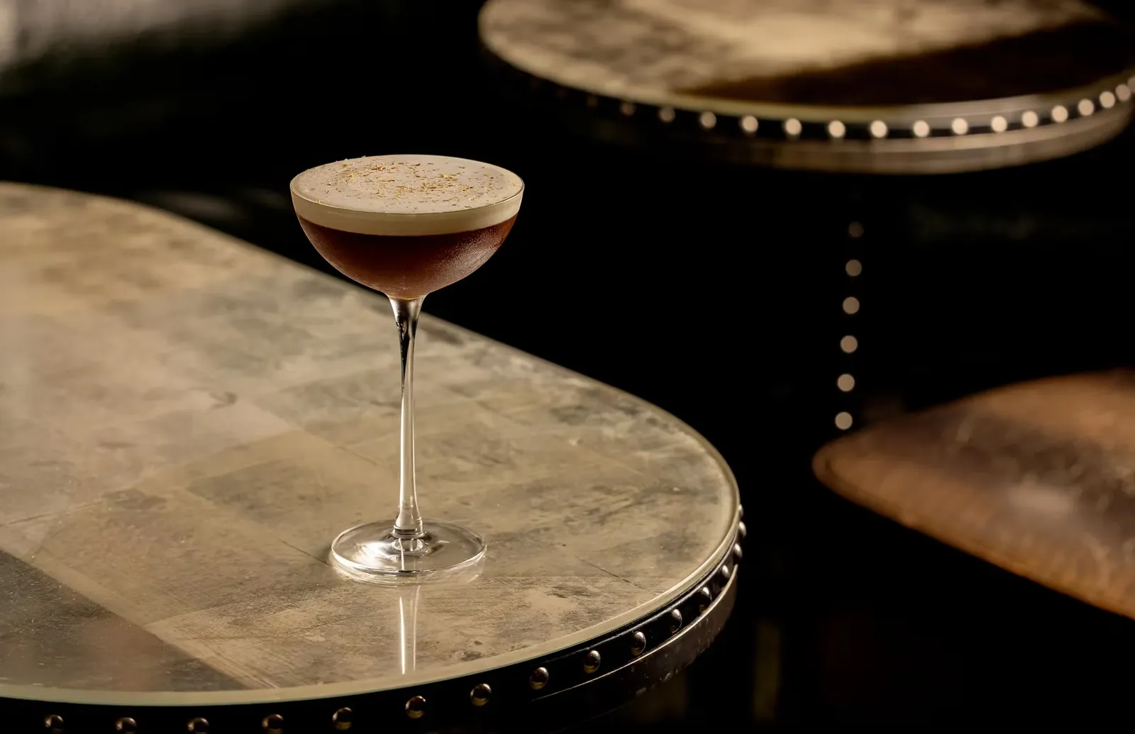 A dark cocktail served in a coupe on a marble table at The Connaught Bar