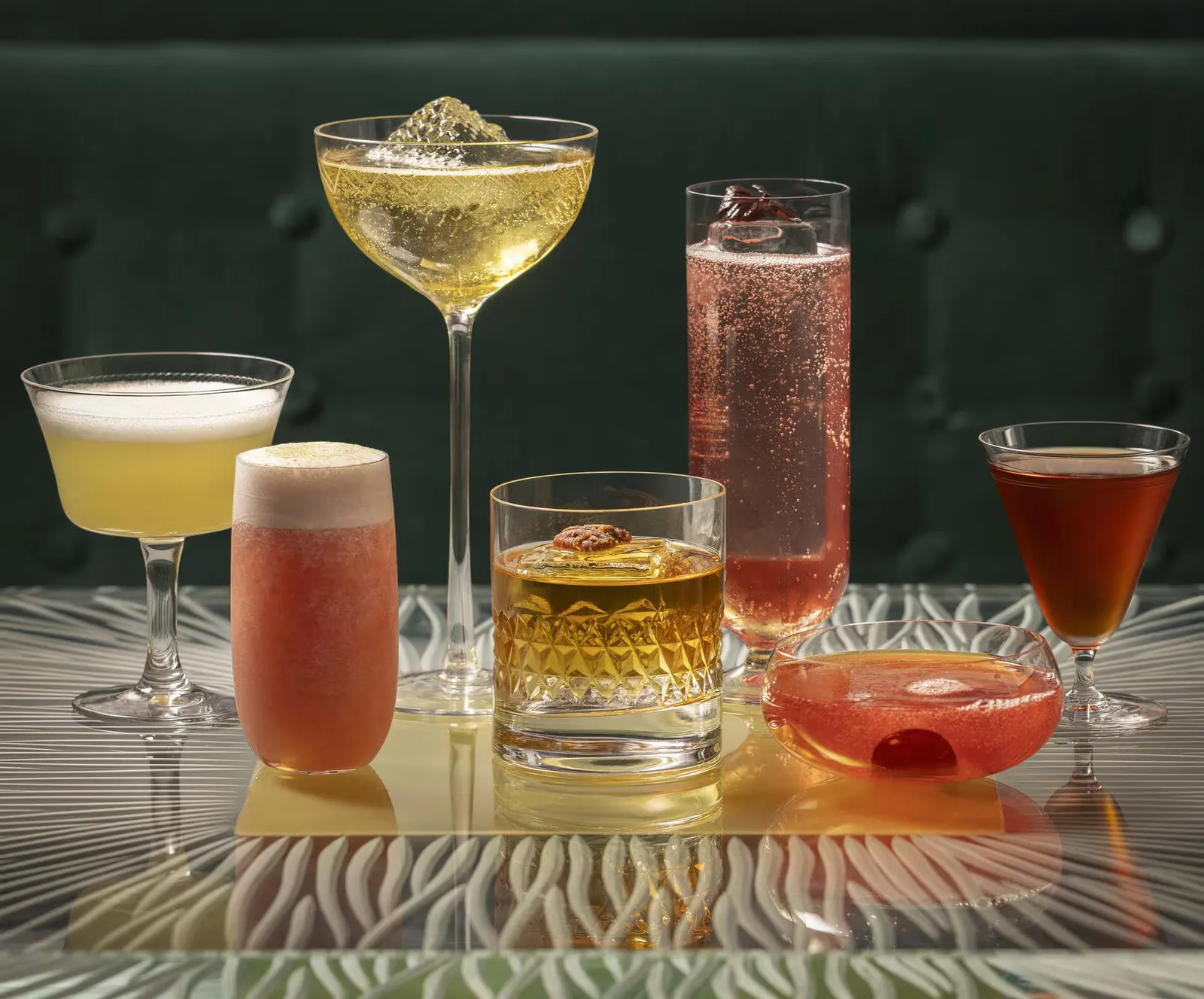 A selection of colorful cocktails arranged in front of a green banquette at The Donovan Bar
