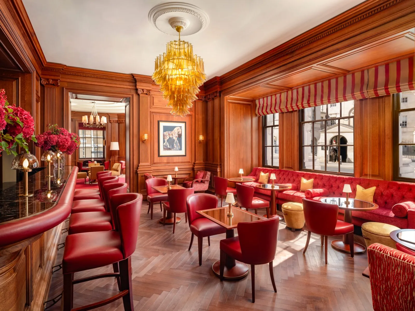 The bar and red seating beside Horse Guards facing windows at The Guards Bar and Lounge