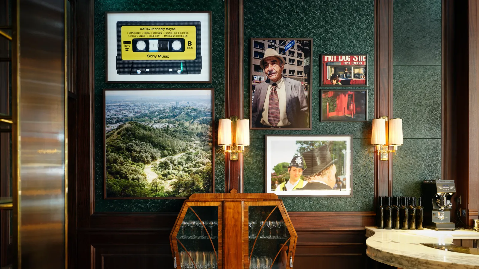 Framed photographs and yellow cassette artwork on the dark green walls at Side Hustle