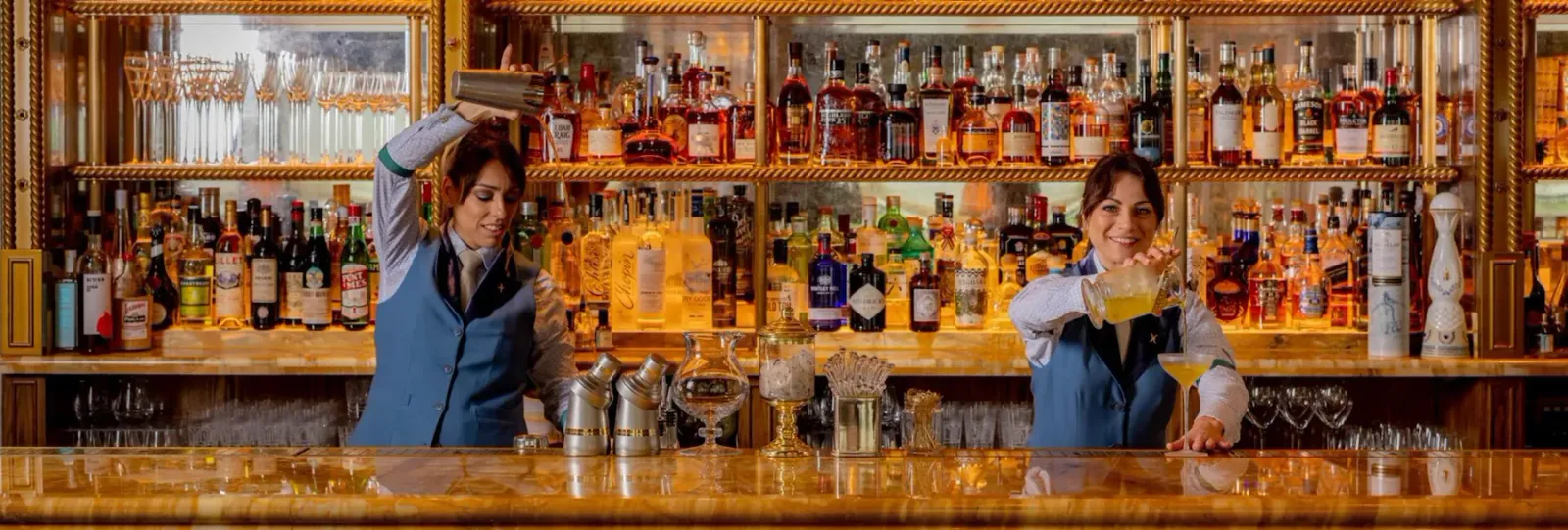 Two bartenders preparing cocktails behind the bar at Vesper Bar